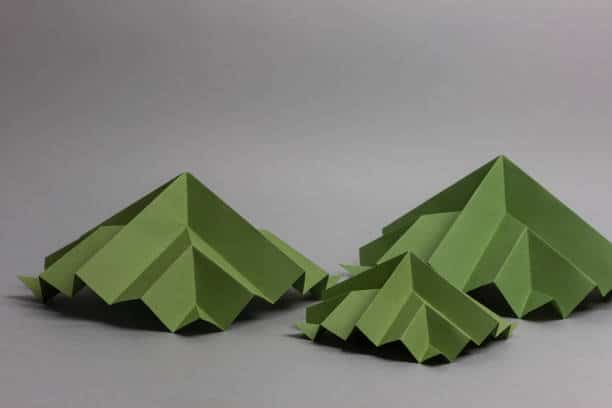 Origamis en papier vert : trois pyramides pour représenter des maisons